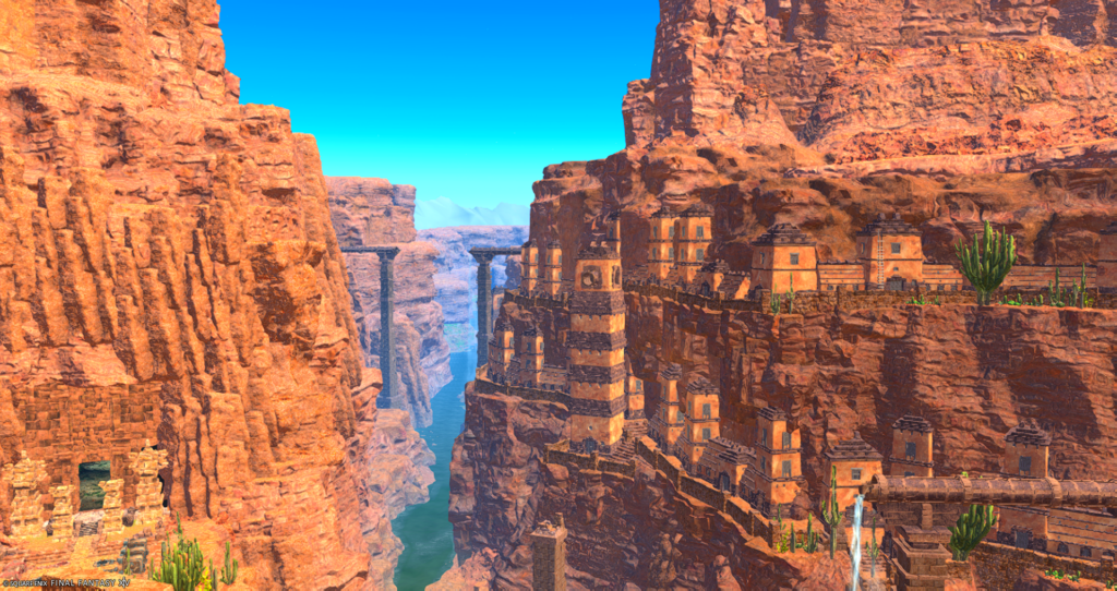 A screenshot from the video game FFXIV. This image depicts a stone city built into the side of a cliff, with a narrow river in a gorge running off in the distance.